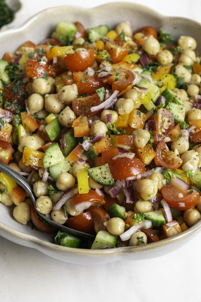3/4 close up of chickpea salad in a bowl with a spoon.