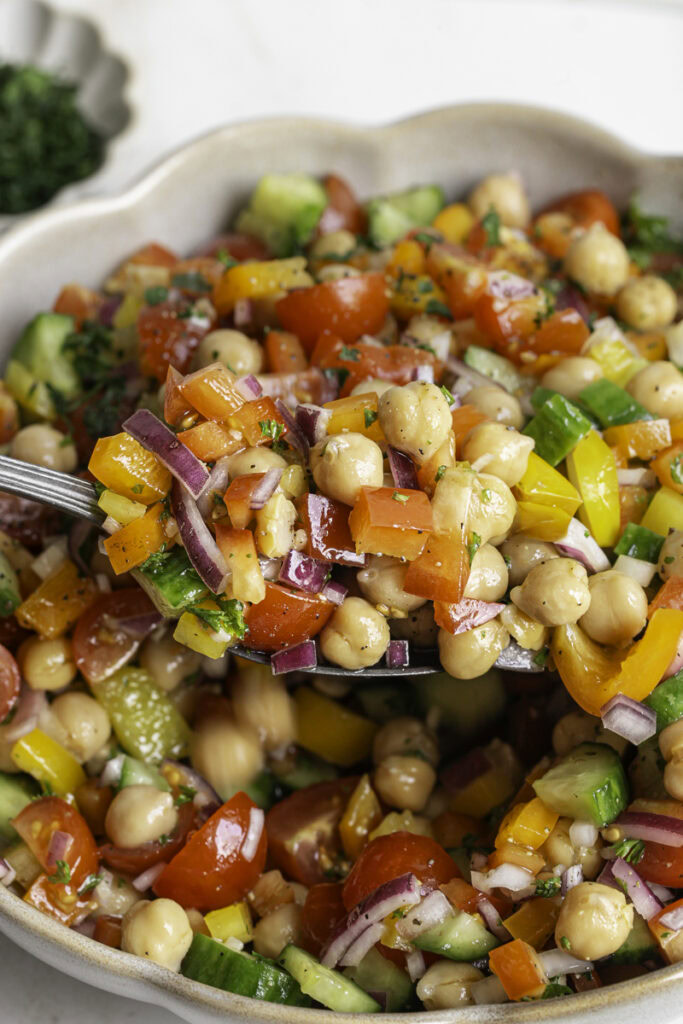 scooping some chickpea salad out of the bowl with a spoon.