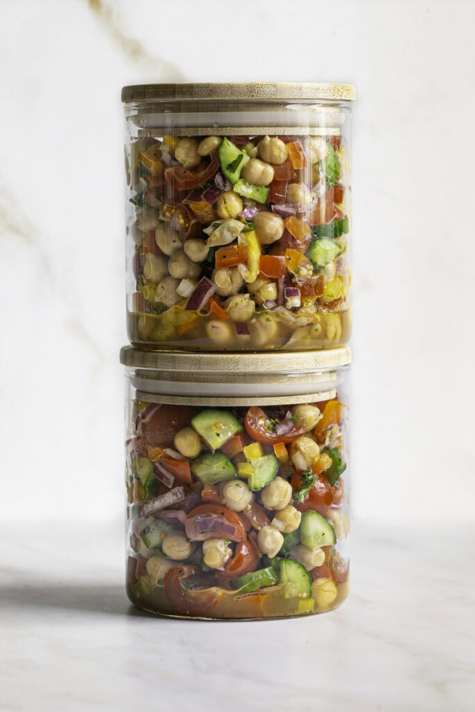 chickpea salad in glass storage jars stacked on top of one another.