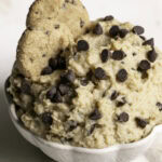 a bowl of High Protein Almond Flour Chocolate Chip Cookie Dough Dip with two mini chocolate chips cookies in it.
