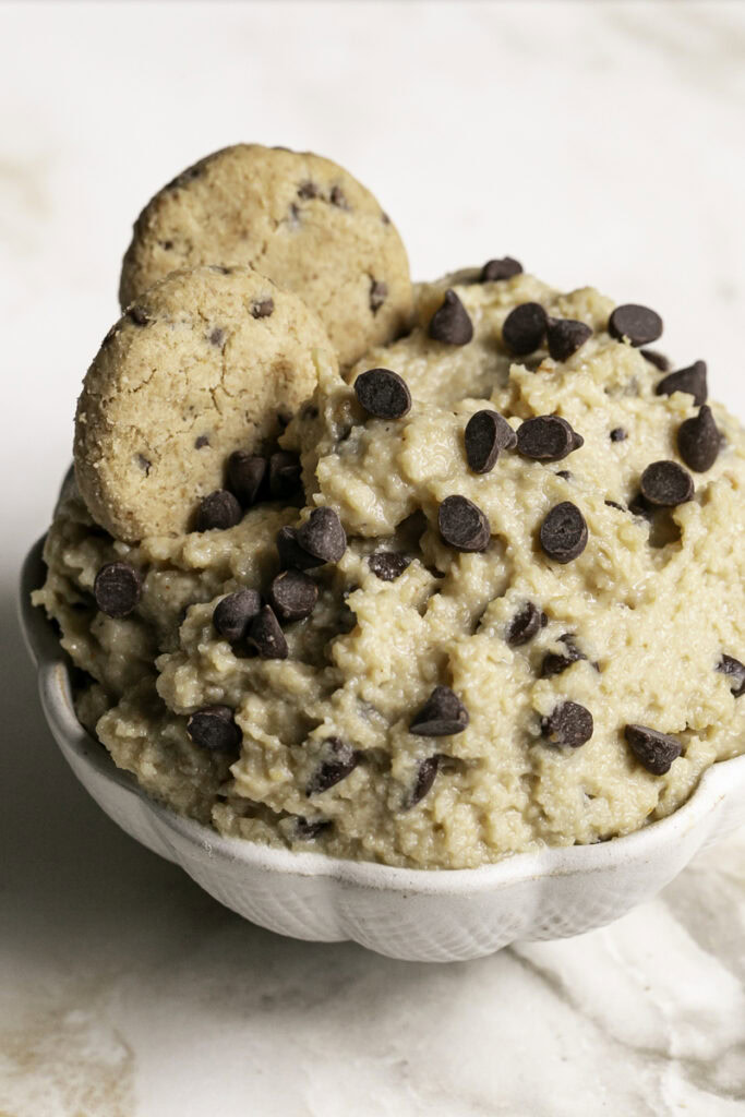 a bowl of High Protein Almond Flour Chocolate Chip Cookie Dough Dip with two mini chocolate chips cookies in it.