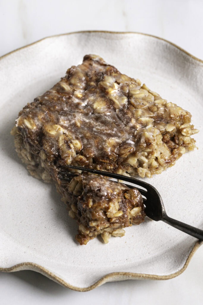 a slice of cinnamon roll baked oatmeal on a plate with a fork.