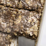 close up of sliced cinnamon roll baked oatmeal in a baking dish with a spatula and a slice missing.