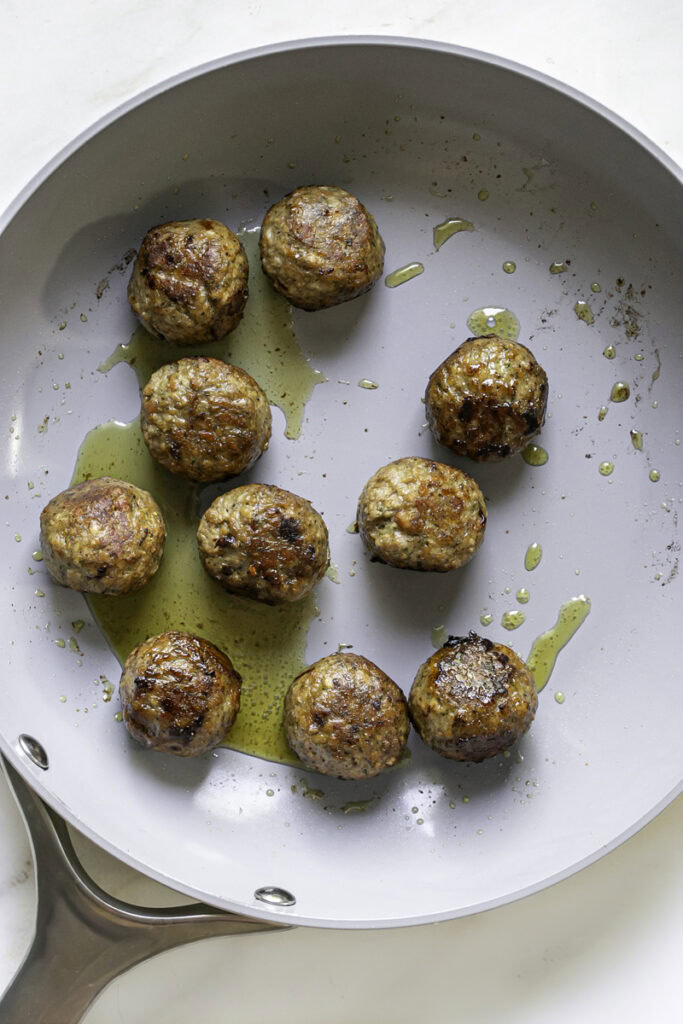 cooked vegan meatballs in a skillet with olive oil.