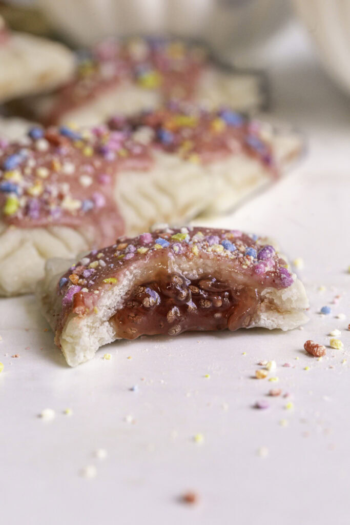 close up of a strawberry chia jam mini pop tart with a bite taken out of it to reveal the strawberry chia jam filling.