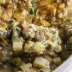 close up of spooning some creamy vegan breakfast hashbrown casserole out of the casserole dish with a spoon.