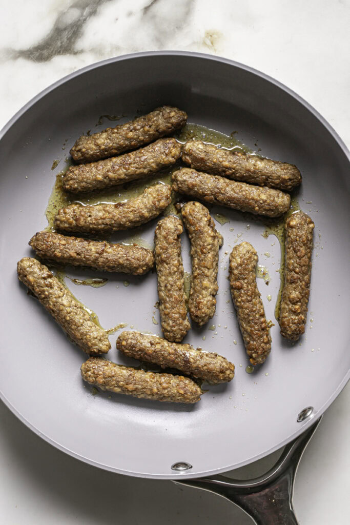 cooked vegan sausage links in a skillet.