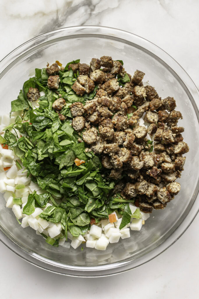 fresh chopped spinach and chopped vegan sausage added to the bowl with the frozen potatoes.