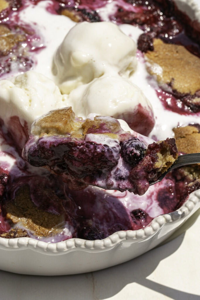 scooping cookie berry cobbler out of the dish.