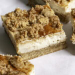a close up of a slice of cinnamon cookie cheesecake crumb bar.