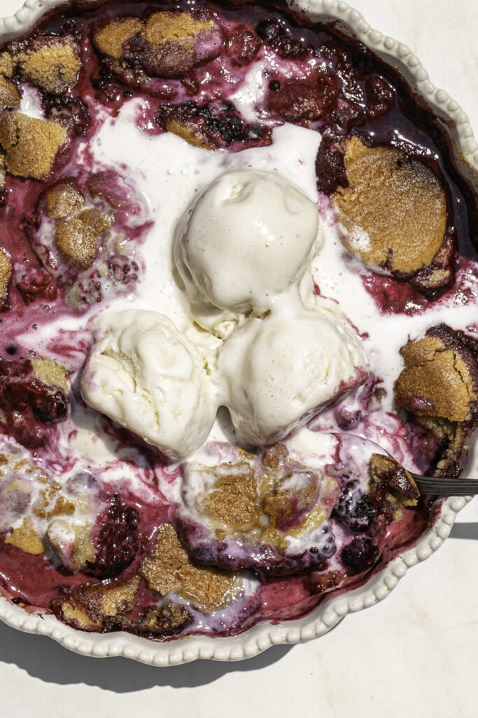 cookie berry cobbler with melting vanilla ice cream on top.