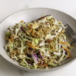 a bowl of crunchy ramen noodle cabbage salad with a fork.
