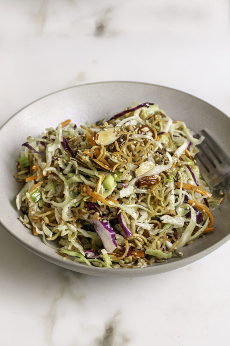 a bowl of crunchy ramen noodle cabbage salad with a fork.
