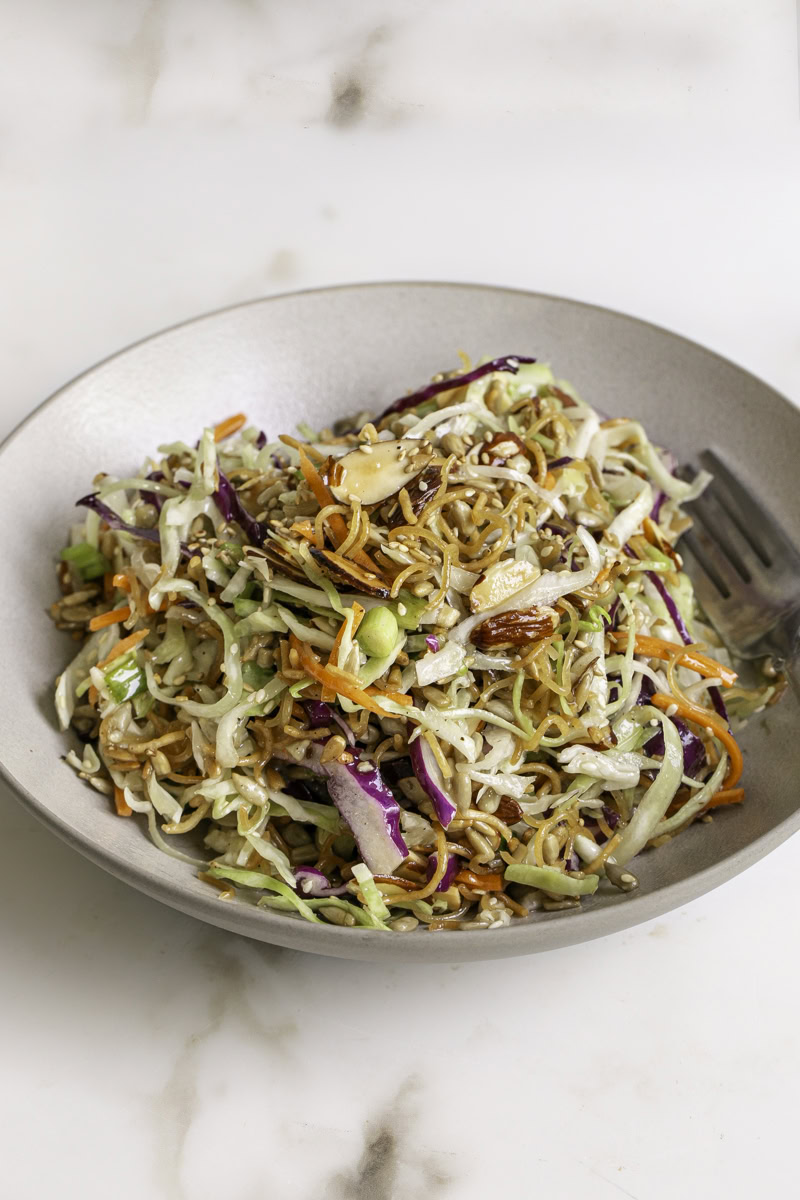 a bowl of crunchy ramen noodle cabbage salad with a fork.