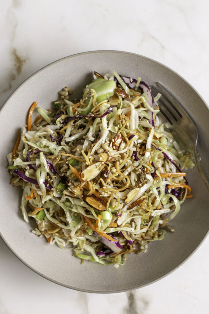 overhead shot of a bowl of crunchy ramen noodle cabbage salad with a fork.