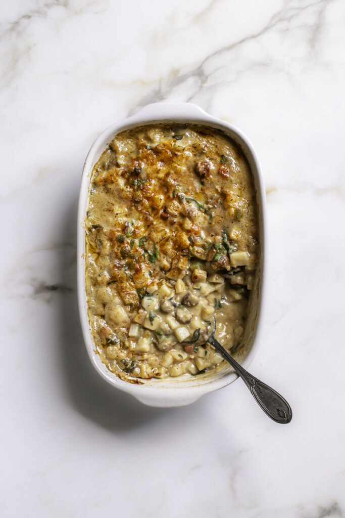creamy vegan breakfast hashbrown casserole with some of the casserole spooned out.