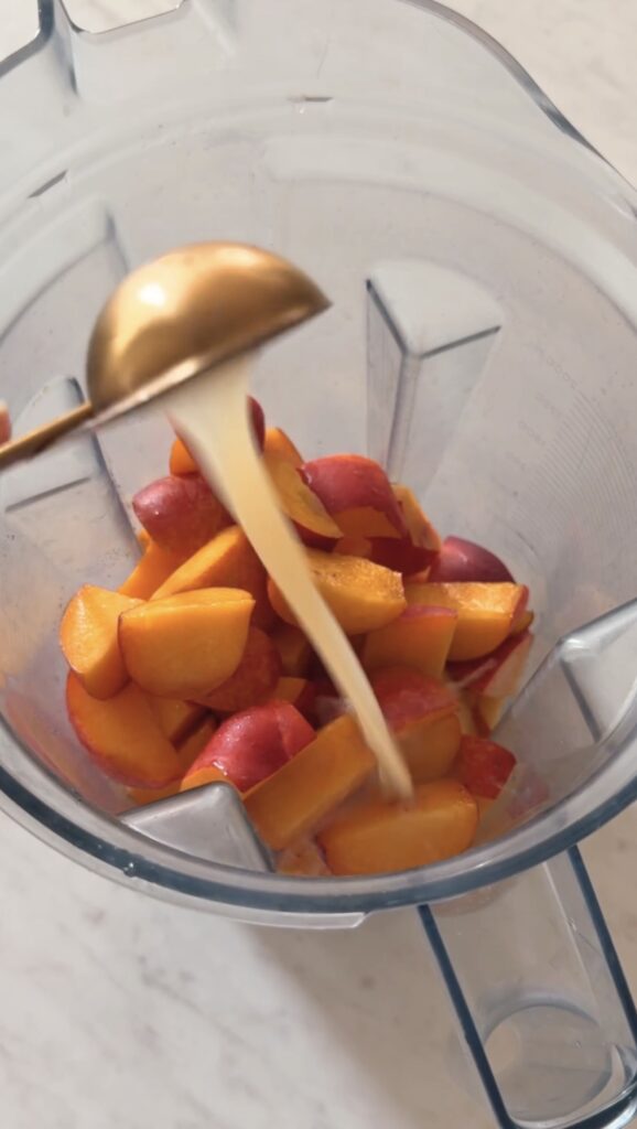 pouring lemon juice into the blender with the chopped nectarines.