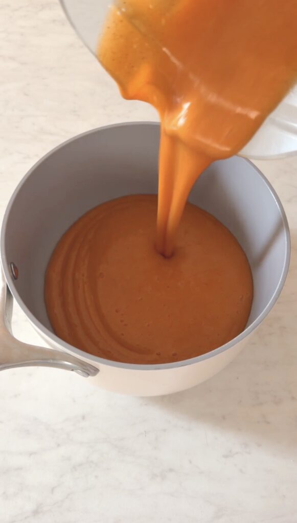 action shot pouring the blended nectarine puree into a saucepan.