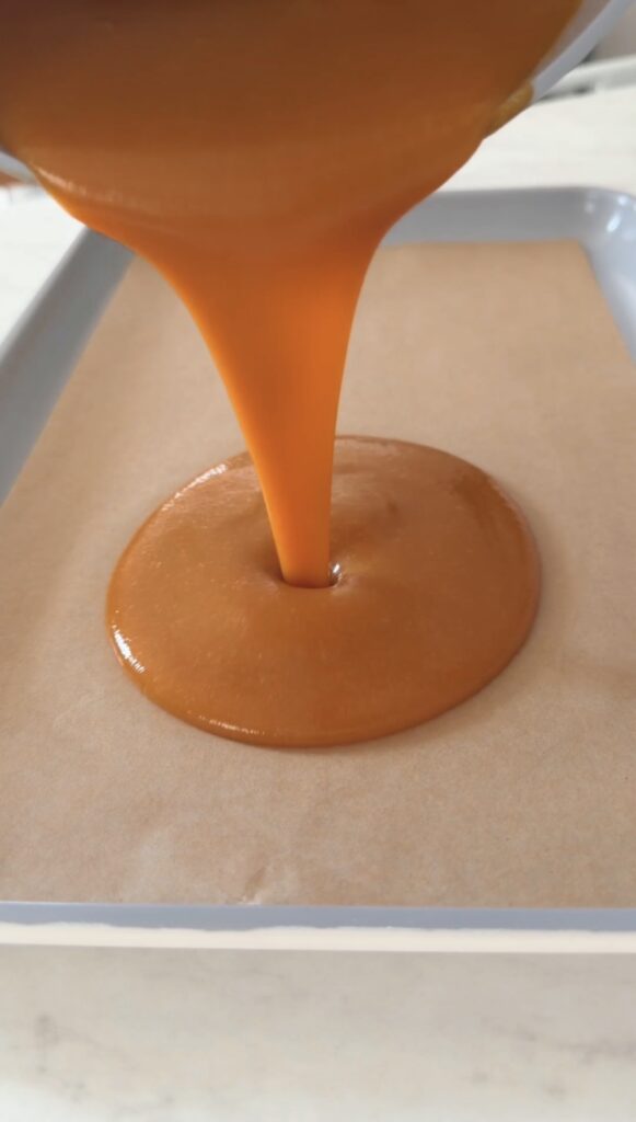 pouring the nectarine puree onto a parchment lined baking sheet.