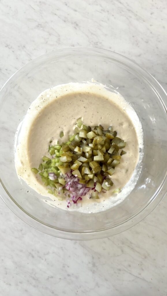 chopped celery, red onion, dill pickles added to the bowl with the dressing.