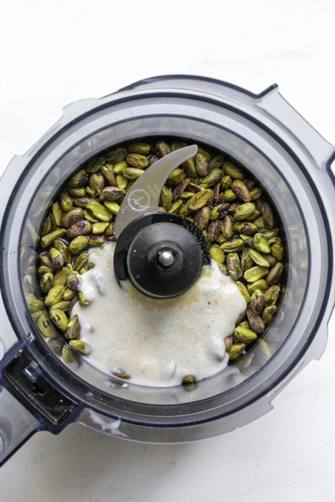 pistachios, yogurt, salt, maple syrup, oat milk, and vanilla added to a food processor.