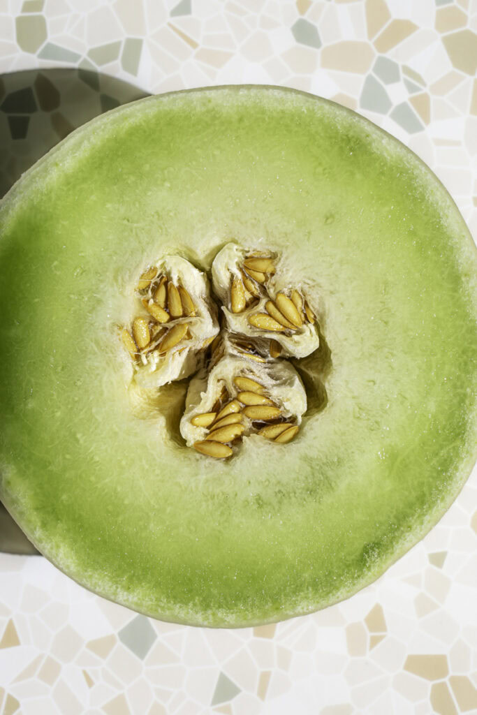 a honeydew melon sliced in half to reveal the seeds inside.