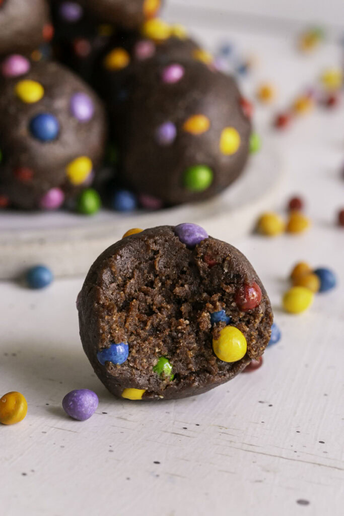 a close up of a Cosmic Brownie Cookie Dough Date Bite with a bite taken out of it.