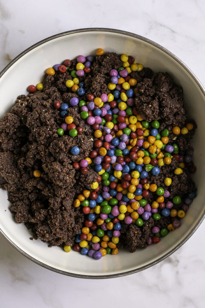 rainbow candy coated chocolate chips in a bowl with the brownie cookie dough.