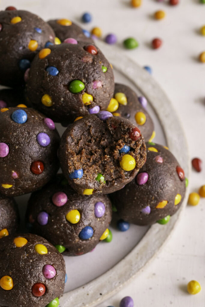 Cosmic Brownie Cookie Dough Date Bites stacked on top of one another, one with a bite taken out of it.
