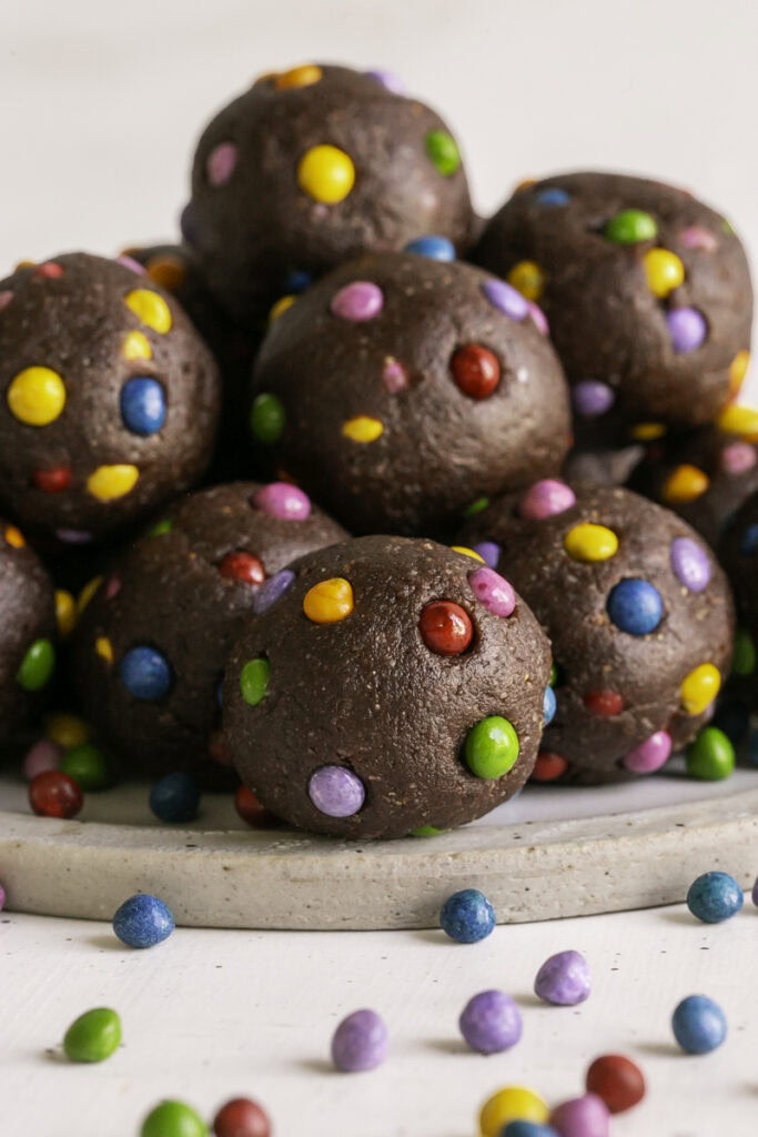 no-bake cosmic brownie cookie dough dates bites stacked on top of one another.