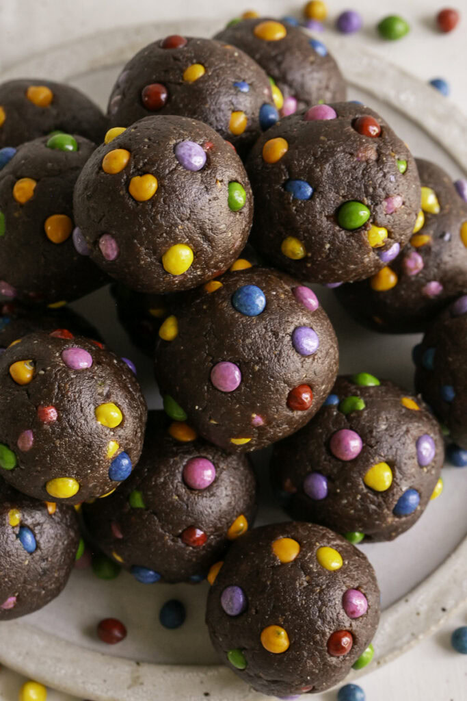 no-bake cosmic brownie cookie dough dates bites stacked on top of one another.