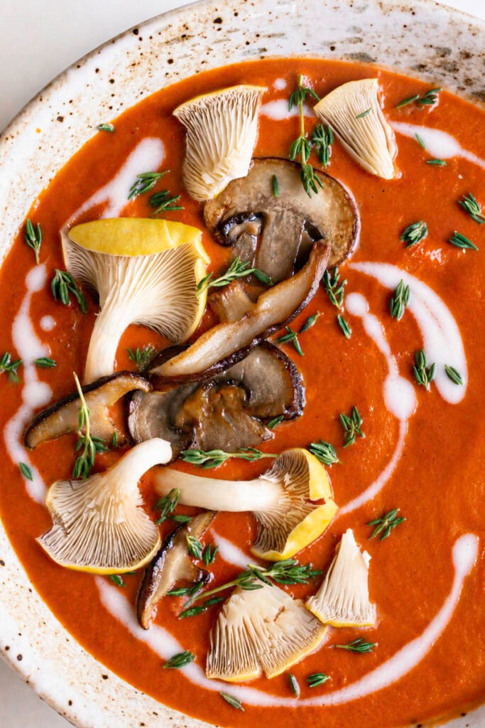 extreme close up of a bowl of Creamy Mushroom Tomato Bisque garnished with mushrooms.