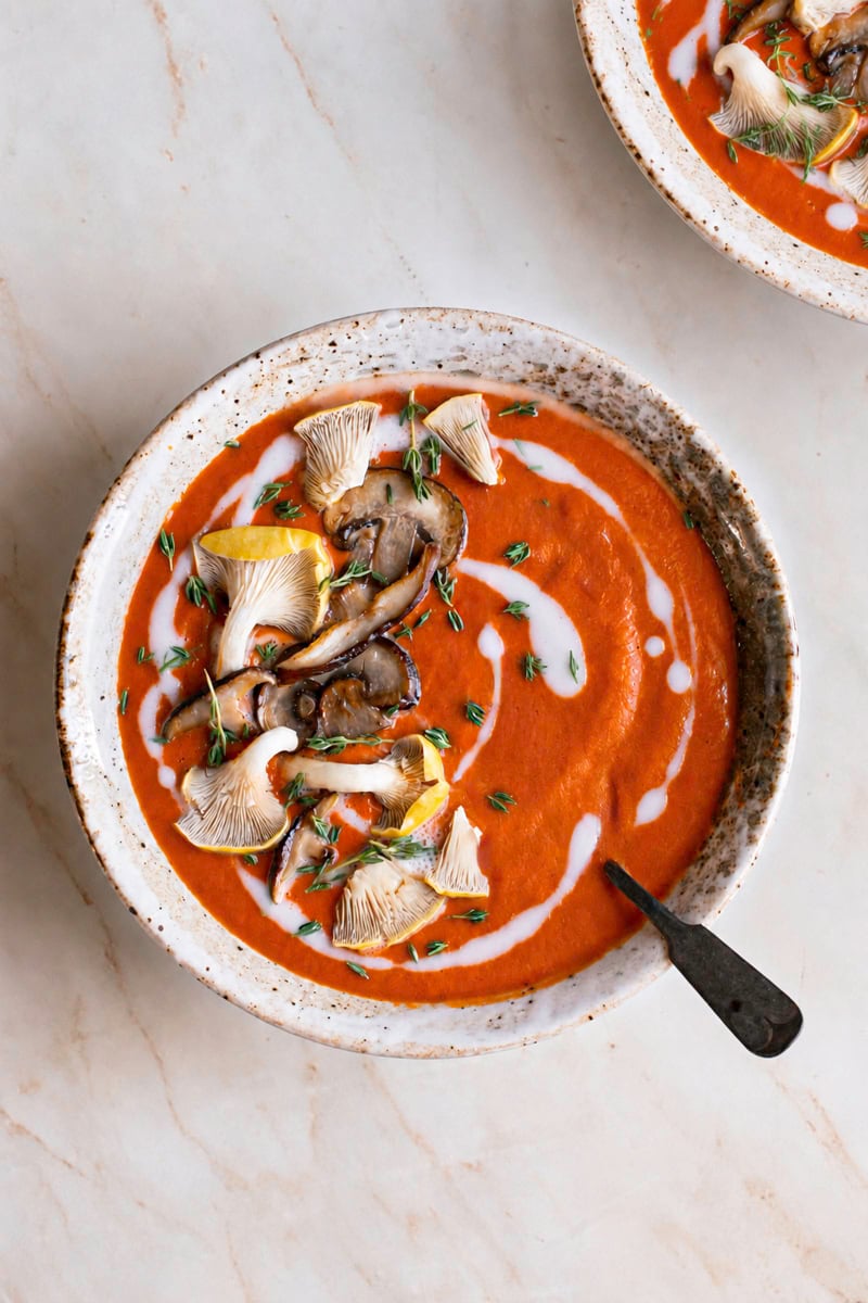 a bowl of Creamy Mushroom Tomato Bisque garnished with mushrooms and a spoon in the bowl.
