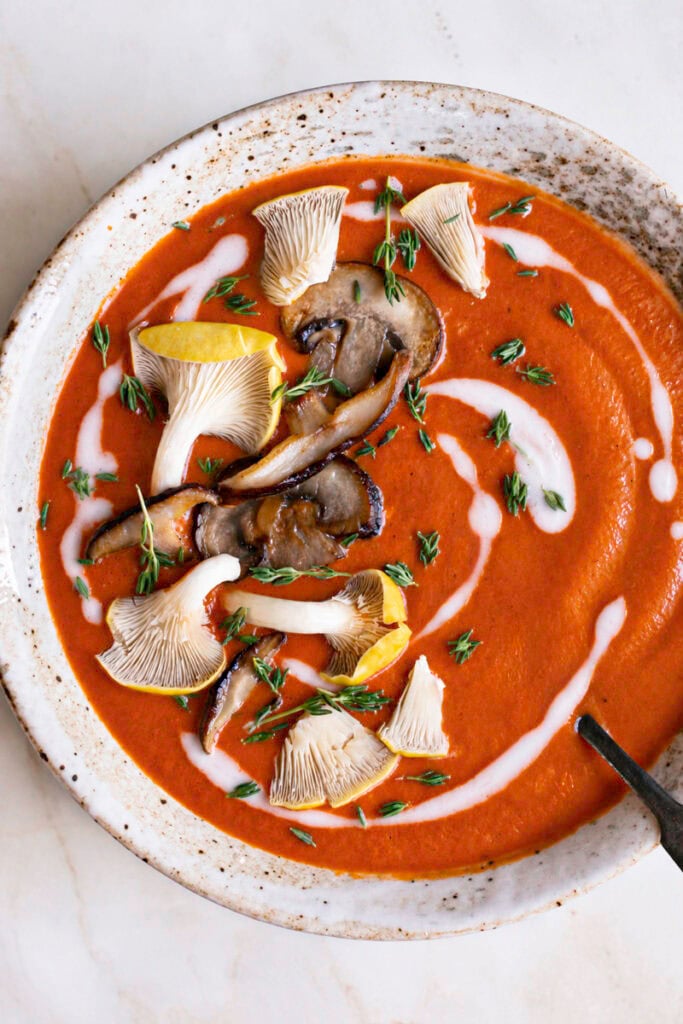 close up of a bowl of Creamy Mushroom Tomato Bisque garnished with mushrooms and a spoon in the bowl.