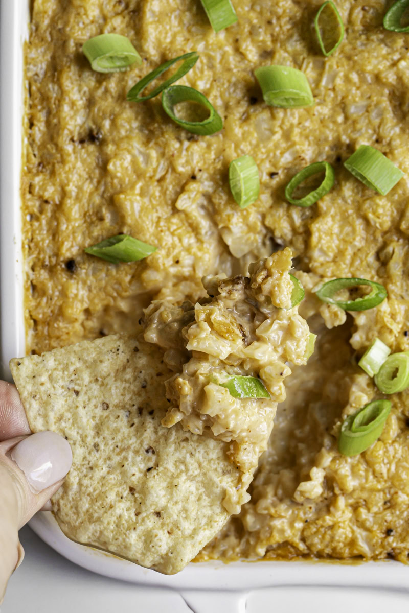 overhead close up shot dipping a tortilla into the buffalo cauliflower dip.
