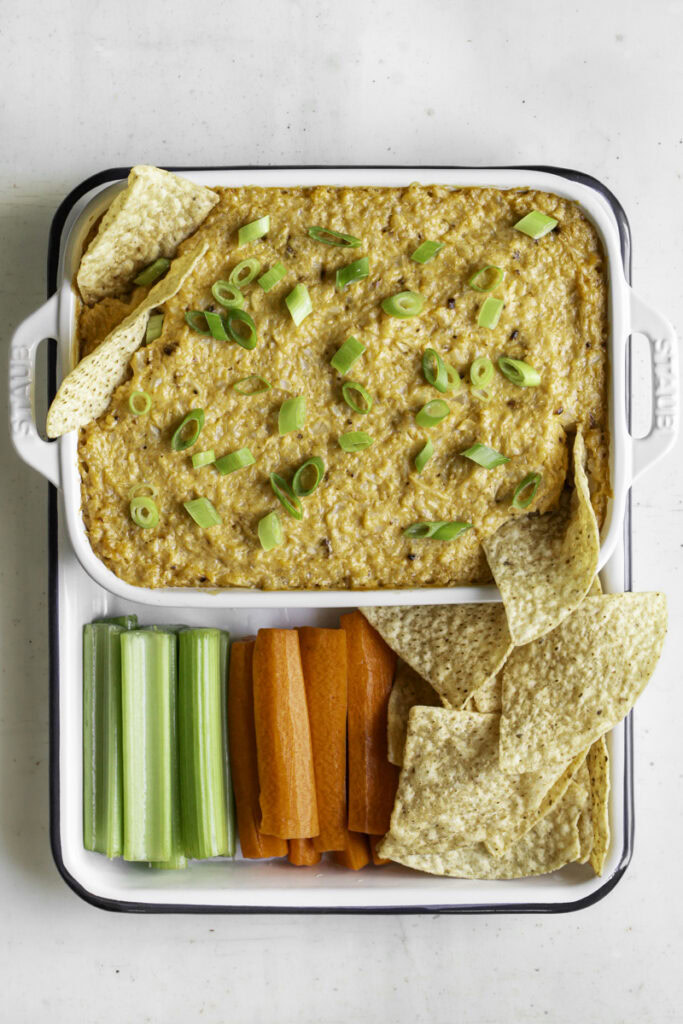 buffalo cauliflower dip served with celery and carrot sticks and tortilla chips.