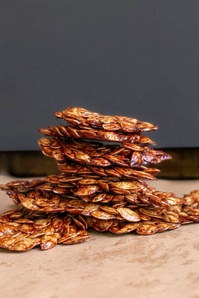 pieces of Maple Cinnamon Sugar Pumpkin Seed Brittle stacked on top of one another.